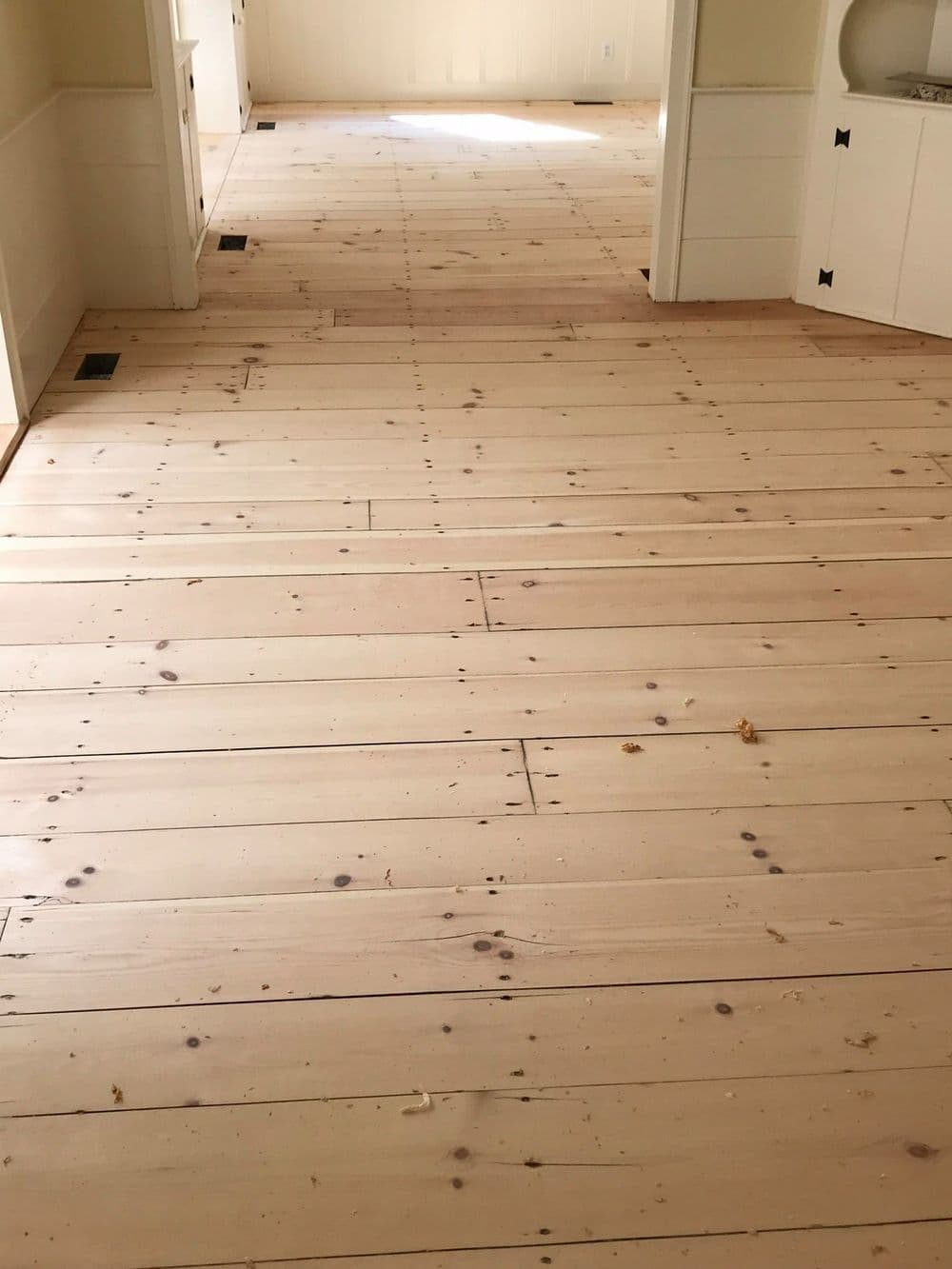 Light-colored wooden floor with wide planks, showcasing natural texture and imperfections.