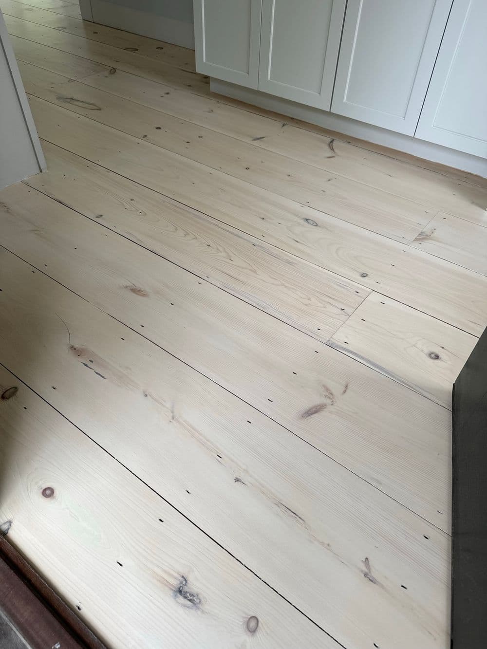 Light wood flooring with knots, showcasing a natural finish in a modern kitchen setting.