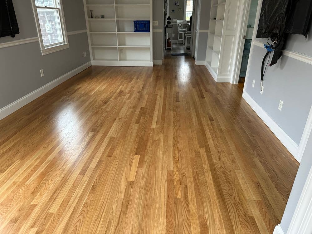 Spacious living room with newly finished hardwood floors and bright natural light.