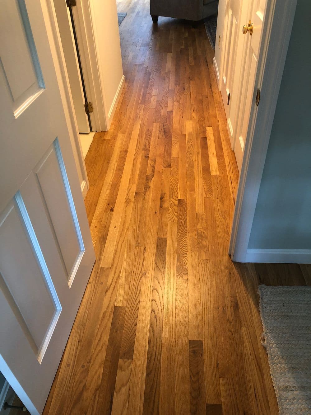 Polished hardwood floor leading to a well-lit hallway entrance in a modern home.